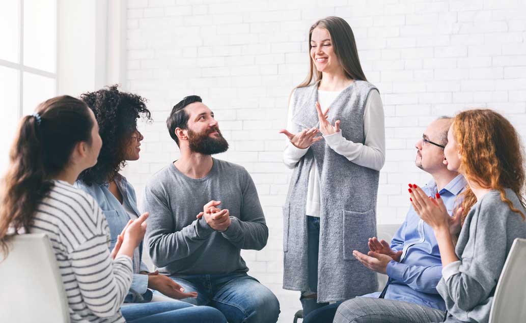 woman-standing-talking-with-group-sitting-in-circle