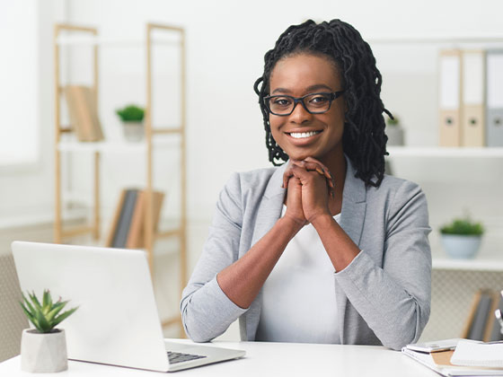 smiling woman sitting at desk with laptop